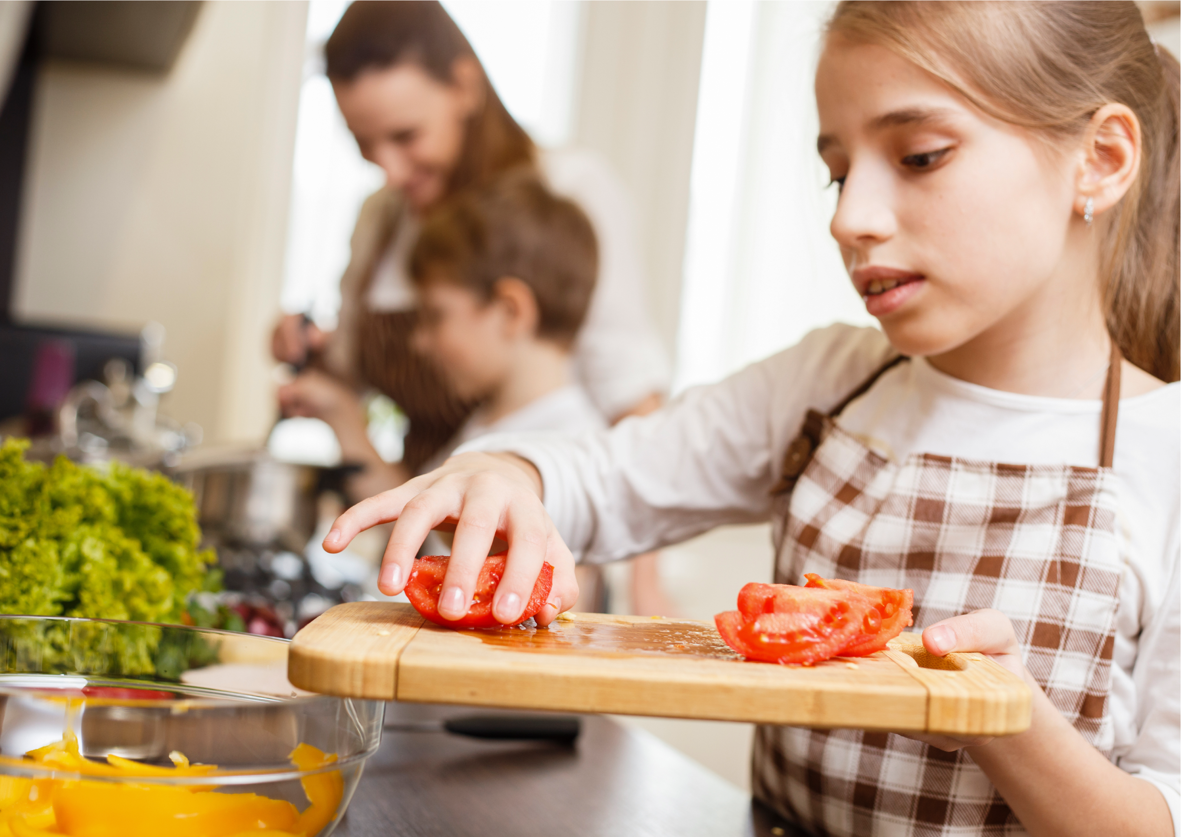 Young blonde-haired girl putting chopped tomatoes into a bowl.